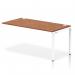 The photograph shows a sleek white frame office bench desk with a walnut finish. The dynamic bench desking system features a single row extension kit, adding extra space for productivity. This modern desk setup is both functional and aesthetically pleasing.