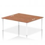 This picture features a sleek white frame office bench desk with a 2 person capacity. The dynamic bench desking style creates a modern and functional workspace. The desk is accented with a beautiful walnut finish, providing a warm and inviting touch.
