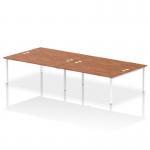 The photo shows a modern and versatile office bench desk with a white frame and a walnut top. It can accommodate four people and is designed for use in a B2B setting. The dynamic design of the bench provides a sleek and functional workspace for any office.