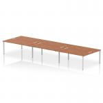 The photograph shows a spacious and modern office setting with a dynamic bench desking arrangement. The Impulse Bench B2B can accommodate up to 6 people, with a sleek silver frame and a sophisticated walnut finish on the office bench desk.