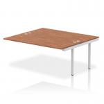 This picture shows a stunning Dynamic Bench Desk with Add On Units, featuring a sleek silver frame and a gleaming walnut surface. With its spacious design and modern aesthetic, this Impulse Bench B2B Ext Kit is perfect for any contemporary office space.