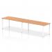 The photograph depicts a sleek and modern office bench desk, with two people seated at the Dynamic Bench Desking Impulse Bench. The desk features a 1800 white frame and is topped with an oak wood surface. The single row design creates a dynamic workspace for collaborative productivity.