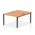 The image shows a modern, sleek bench desk with a black frame and oak top. It is designed for office use and can comfortably accommodate two people. The dynamic design of the bench allows for easy collaboration and productivity.