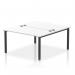 In the photo, two people are shown sitting at the Dynamic Bench Desking Impulse Bench B2B. The desk has a sleek black frame with a 1400 size, and the seat and backrest are in a modern white color. The clean, contemporary design makes it perfect for any office setup.
