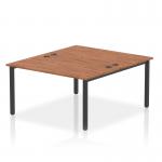 The photograph captures a modern and innovative office setup with a dynamic bench desking system. The Impulse Bench B2B, designed for 2 people, features a sleek black frame and a timeless walnut office bench desk.