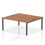 The photograph captures a sleek and modern two-person bench desk with a striking black frame and a warm walnut finish. The dynamic design allows for comfortable and functional use in any office space.