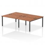 The photograph captures a sleek and modern Dynamic Bench Desking Impulse Bench B2B, designed for four people. The desk has a black frame with a smooth walnut finish, creating a sophisticated and professional look for any office space.