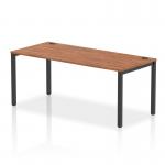 In the photo, a sleek and modern dynamic bench desking setup can be seen. The single row of desks features a black frame and a striking walnut finish, adding a touch of sophistication to the office space. The desks are arranged in a 1800 configuration, providing ample work surface for users. Overall, the dynamic bench desking setup exudes professionalism and efficiency.