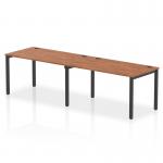 The photograph captures a sleek and modern dynamic bench desking setup, with a single row featuring a 2 person capacity. The black frame provides a sturdy base for the beautiful walnut office bench desk, creating a balanced and stylish workspace.