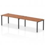 The photograph features a dynamic bench desking system with a single row of two person desks. The black frame adds a sleek touch to the office space, while the walnut desks provide warmth. The overall design is modern and professional, perfect for a collaborative work environment.