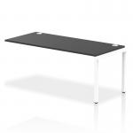 The photograph shows a sleek, modern office space with a row of dynamic bench desk add-on units equipped with a single row extension kit. The desk has a white frame and the bench itself is black, creating a professional and stylish look.