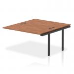 The photograph shows a sleek, modern-looking Dynamic Bench Desk with Add On Units and Impulse Bench B2B Extension Kit, all in a striking black frame. The desk is topped with a rich walnut finish, creating a stylish and professional office bench desk.