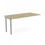 This photograph features an urban oak-colored office bench desk with add-on units, specifically the C-sense 1 person bench add-on portal top measuring 1600 x 800. The sleek desk is topped with a modern silver frame, giving off a professional and stylish vibe.