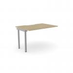 The picture shows a sleek office bench desk with add-on units. Its scallop top is made of urban oak, giving it a stylish look. This desk is designed for one person and measures 1000 x 800. The add-on units are in a modern silver and urban oak color.