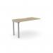 The photo captures a modern desk unit with a sleek urban oak finish. Its scallop top adds a touch of elegance to its design, while its added units provide extra space for work essentials. The silver accents add a stylish touch to the overall aesthetic of the workspace.