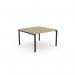 The photograph captures a sleek and modern office bench desking setup. The open-leg design with a portal top gives a spacious and airy feel. The 1 person bench is finished in urban oak with black accents, creating a sophisticated look.