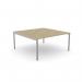 The picture shows an Edit Office Bench Desking C-sense with a single person sitting at an open leg bench. The top features a scallop design and measures 1600 x 800, with an urban oak finish and silver accents.