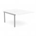 The photo shows a white desk with scallop-shaped tops, designed to accommodate two people. Add-on units are attached to the sides of the main desk, creating a spacious and functional workspace. The sleek design and silver accents give a modern and professional look to the office bench.