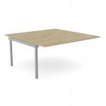 The photograph displays two C-sense bench add-on units with scallop tops in Urban Oak finish. These 1600 x 800 desks are seamlessly connected to create a spacious and modern work area for two people. The sleek SLV accents add a touch of sophistication to the overall design.