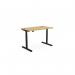 The photograph shows a round, curved bamboo top desk with a black frame. It is an adjustable height desk, with the dimensions 1200 x 700mm. It is designed for use in an office setting, allowing for both sitting and standing positions.