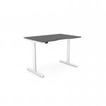 The photo shows an Edit Office Sit Stand and Height Adjustable Desks RoundE with a double purpose scallop. The desk measures 1200 x 800mm and has a graphite white frame. It appears sleek and modern, with a clean white surface and curved edges. The desk is set at a standing height and has the option to be adjusted for sitting as well. It is ideal for use in an office or workspace.