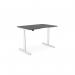The photo shows an Edit Office Sit Stand and Height Adjustable Desks RoundE with a double purpose scallop. The desk measures 1200 x 800mm and has a graphite white frame. It appears sleek and modern, with a clean white surface and curved edges. The desk is set at a standing height and has the option to be adjusted for sitting as well. It is ideal for use in an office or workspace.