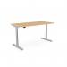 The photo features a sleek round-shaped sit stand desk with height adjustability and a built-in aluminum portal. The desk has a beech top and silver frame, with a spacious surface measuring 1600 x 800mm. The design is modern and functional.