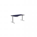 The photo shows an office space with sit stand and height adjustable desks. The desk has a black top and zoom black legs. The specific dimensions are 1600 x 800 and it is left-handed. The top is black and the overall look is sleek and modern.