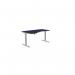 The photo shows an office space with sit stand and height adjustable desks. The desk has a black top and zoom black legs. The specific dimensions are 1600 x 800 and it is left-handed. The top is black and the overall look is sleek and modern.