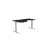 This image shows a modern office space with several curvy, height adjustable desks. The desks have grey legs and a black top, with a left-handed configuration. The overall dimensions are 1600 x 800, and the desks have a sleek, professional appearance.