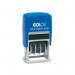 The photo shows a COLOP S120 self-inking mini dater with the brand name COLOP prominently displayed. The ink stamps are in the shape of rectangular blocks, with a small handle for easy use. The dater is in black and red ink, with visible markings for the date and other details.