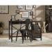 The picture shows a sleek and modern Teknik SoHo Furniture home office desk with a sturdy steel frame in a gorge wrought iron style. The desk has a dark carbon oak finish and features ample workspace for a comfortable and functional setup.