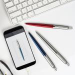 The photo showcases a professional Newell Brands Parker pen and refill set in a beautiful gift box. The pen is a Parker Jotter Ballpoint with a sleek red and chrome design, complemented by a blue ink refill. Perfect for any writing needs with a touch of style.