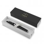 The photo shows a sleek and elegant black and chrome Parker IM rollerball pen resting on top of a gift box, accompanied by Parker brand pens and refills from Newell Brands. The pen writes in smooth black ink, making it a perfect writing tool for any occasion.