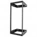 The photograph captures a sleek, modern network rack standing against a wall. The black frame contrasts against the white wall, with multiple routers and switches neatly arranged on the shelves. The 24U rack appears sturdy and durable, perfect for organizing a heavy-duty network setup.