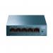 In the image, there are multiple TP-Link routers and switches with a 5-port Gigabit desktop switch in the center. They are all compact and sleek with a white and grey color scheme. The switch has five ports labeled 1-5 and LED indicator lights. The routers and switches have various ports and buttons on the front and back.