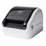 A Brother Label Makers Brother QL-1100C Desktop Label Printer 33247J can be seen in the image. It is a compact label maker with a sleek design, featuring a QL-1100C model number. The printer has a white body with black buttons and labels, and a Brother logo can be seen on the front panel. The label maker is sitting on a desk, next to a keyboard and a computer screen. Its size and design make it a suitable choice for a variety of labeling needs.