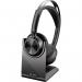 The picture shows a black HP Poly Voyager Focus 2 UC wireless headset with a sleek design and cushioned ear cups. It comes with a USB-C and USB-A adaptor and a stand for convenient storage.