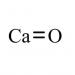 The picture shows a one-kilogram lump of calcium oxide, used for technical purposes, next to school stationery such as pencils, pens, and rulers. The packaging for the calcium oxide is plain and simple, with bold lettering indicating the product name and weight. The stationery items are neatly arranged around the lump, with some overlapping slightly. The background is a clean, white surface, making the products stand out. The image is well-lit, showcasing the sharp edges and smooth surfaces of the stationery and the lump of calcium oxide.