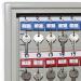 In the image, there is a wall-mounted Phoenix Key Cabinet KC0071K with a sleek, silver exterior. The cabinet has a capacity of 50 keys and features multiple rows of hooks inside for organized storage. The front of the cabinet has a key lock for secure access. Its compact size makes it suitable for various settings.