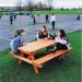 The photo captures a serene outdoor scene with slingsby benches and wooden outdoor picnic tables scattered throughout. The warm wooden tones contrast beautifully with the lush green surroundings, creating a perfect spot for relaxation and outdoor gatherings.