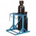 The photograph captures a sturdy floor stand with two sides, designed to hold four slingsby cylinders. The stand has a clean, industrial look, with a silver finish and visible metal bolts. It appears to be in a warehouse or industrial setting, with other equipment and machinery in the background. The cylinders are lined up neatly on each side, creating a symmetrical display. Overall, the stand exudes durability and functionality.