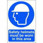 The photograph shows a bright yellow sign with bold black lettering that reads Safety helmets must be worn in this area. The sign is made of 1.2mm recyclable PP and measures 200 x 300mm. The background features a spectrum of colors, creating a vibrant and eye-catching display.