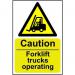 The photograph shows Spectrum Industrial Caution Signs with a bright yellow background and bold black text. The signs read Caution Forklift Trucks Operating in a large font, with smaller text underneath stating the material used (1.2mm Recyclable PP) and the size (200 x 300mm). The signs are rectangular with rounded corners and have a durable, waterproof finish.