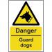 The photo showcases a bright yellow danger sign from Spectrum Industrial with the words Danger Guard Dogs in bold black font. The sign is made from 1.2mm thick recyclable PP material and measures 400 x 600mm. In the background, there are images of aggressive dogs. The sign is designed to warn people of potential danger and to exercise caution in the area.