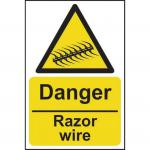 The photo captures a bright red and black danger sign, measuring 200mm x 300mm, warning of razor wire. The self-adhesive vinyl material adds durability to the sign, making it suitable for industrial environments.