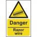 The photo captures a bright red and black danger sign, measuring 200mm x 300mm, warning of razor wire. The self-adhesive vinyl material adds durability to the sign, making it suitable for industrial environments.