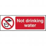 The photograph features a Spectrum Industrial Prohibited Sign for Not Drinking Water, made of self-adhesive vinyl. The sign measures 150mm x 75mm and is labeled with the product number 11676.