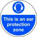 The picture shows a round, anti-slip floor graphic with the words This Is An Ear Protection Zone written in bold letters. The graphic has a white background with a blue border, and the words are in black and yellow. The graphic is laminated for durability and measures 400mm in diameter. It is designed for industrial use and serves as a clear reminder to wear ear protection in the designated area.
