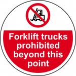 The photograph shows a large, circular floor graphic with the words Forklift Trucks Prohibited Beyond This Point in bold letters. The graphic is anti-slip and laminated for durability. In the background, multiple forklift trucks can be seen. The bright colors and clear font make the message easily visible and attention-grabbing.